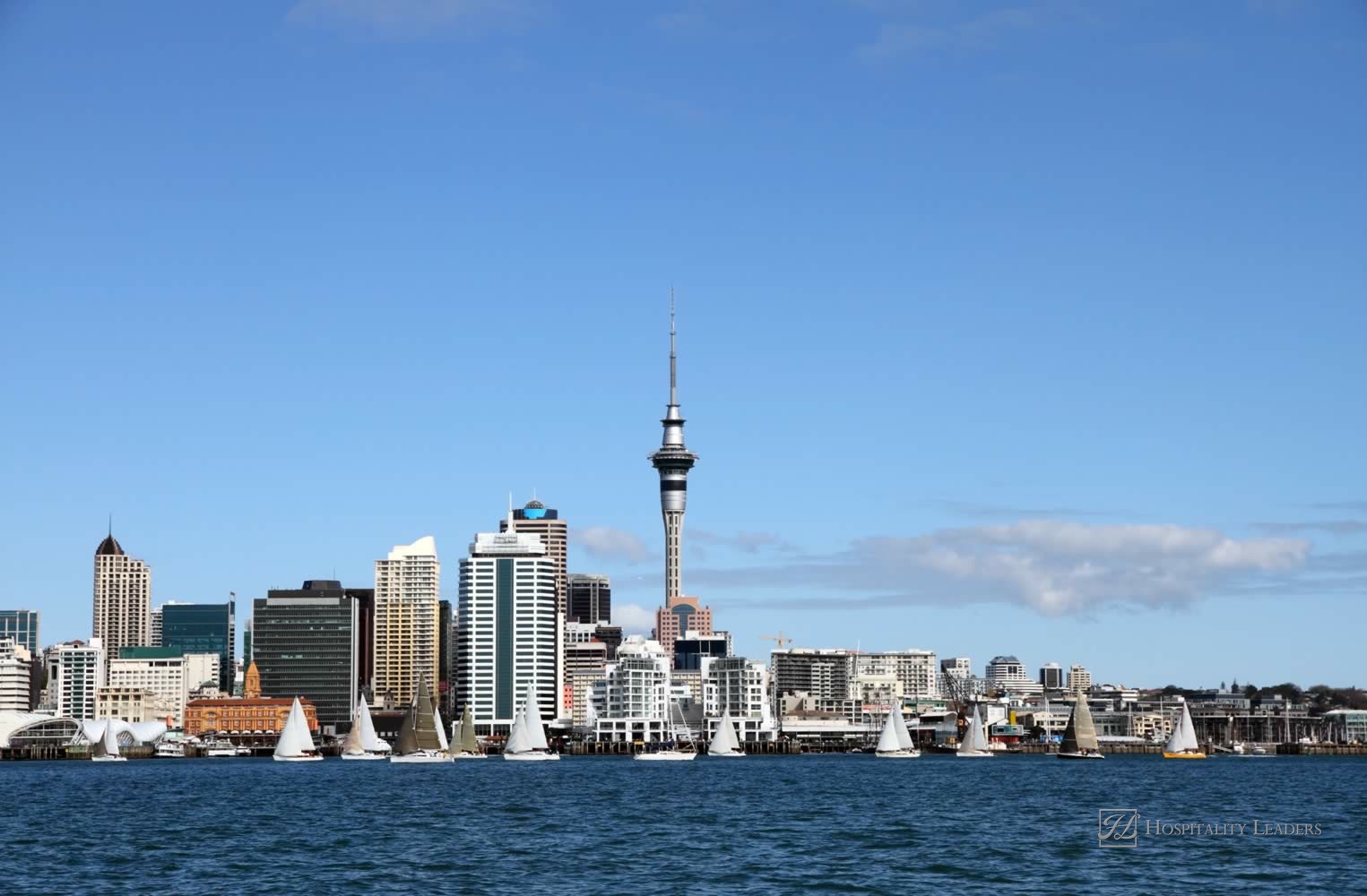 Auckland City and Skytower with yachts sailing past on a clear sunny day. Viewed from across the Waitemata Harbour, Auckland, New Zealand