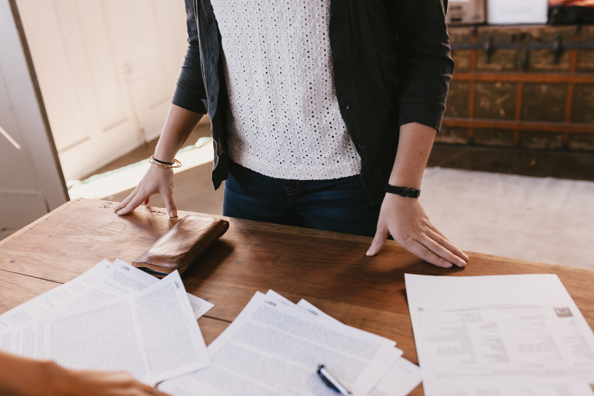 Person standing over desk strewn with paperwork